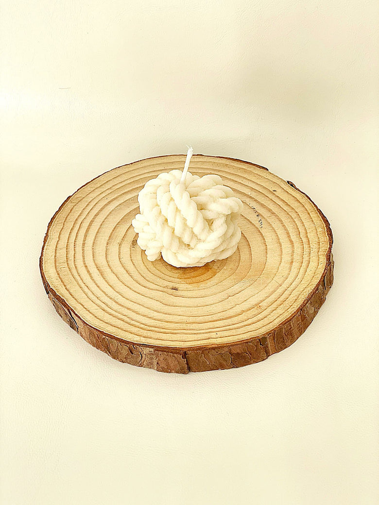 Vela decorativa con forma de ovillo de lana, aunque también puede decirse que es un nudo de cuerdas.  Vela artesanal elaborada con cera de soja en España.